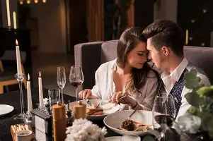 A young couple leans in close during a romantic candlelit dinner at a restaurant.