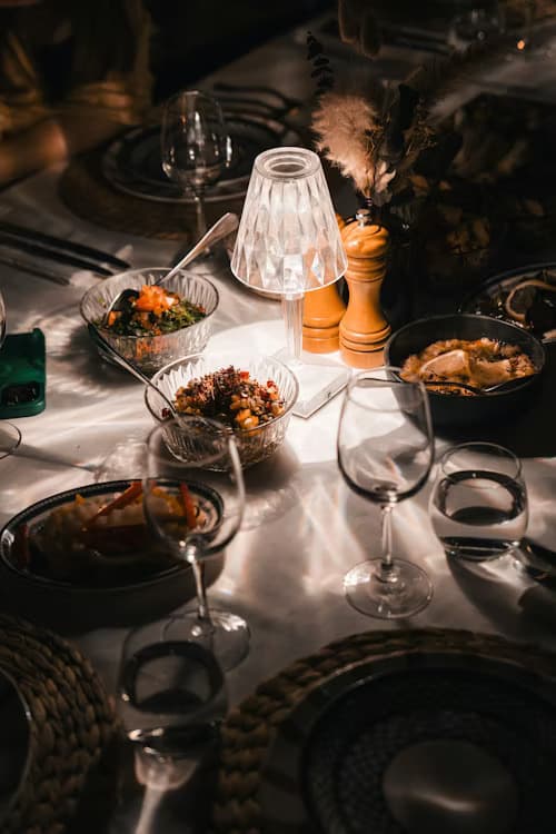 Dimly lit dinner table featuring Mediterranean dishes, wine glasses, and a glowing crystal lamp.