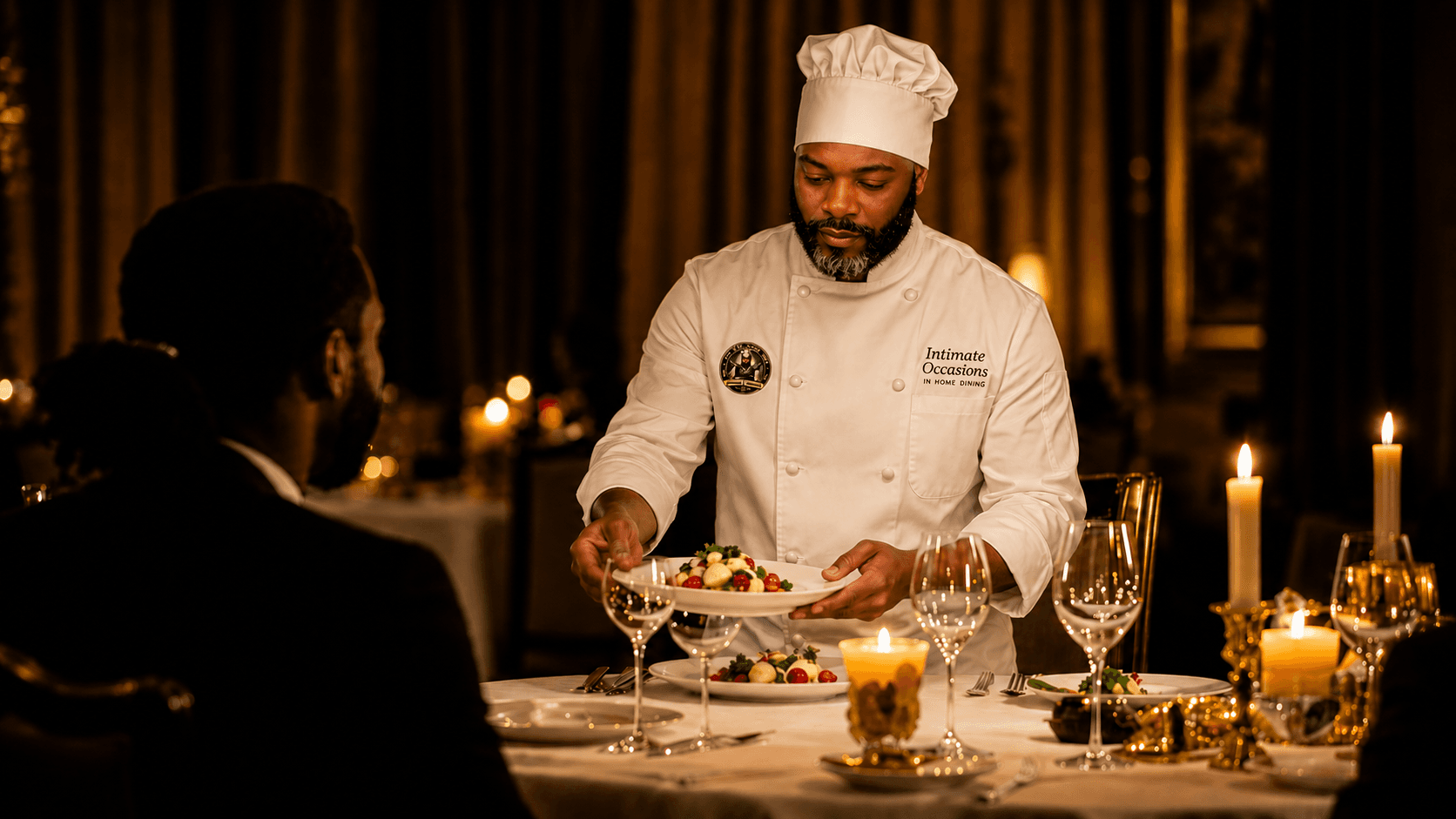 Chef in a white uniform serves a gourmet dish to a diner by candlelight.